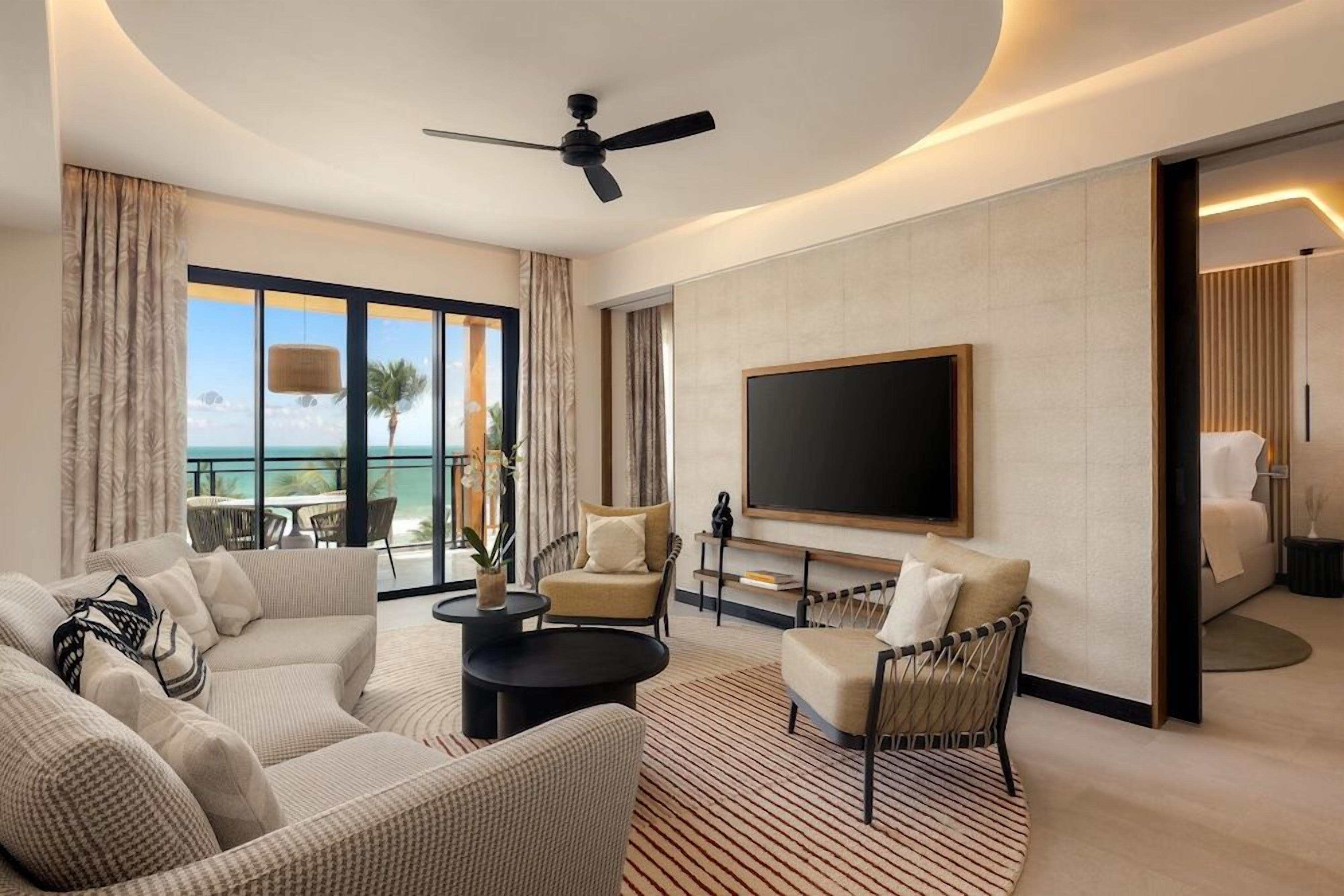 Een moderne hotelkamer met een groot flatscreen televisietoestel, een plafondventilator en uitzicht op de oceaan.