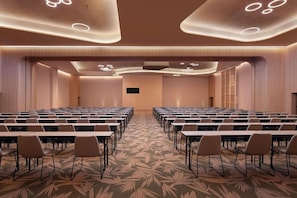A conference room with rows of tables and chairs, a patterned carpet, and a modern ceiling design.