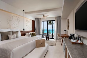 Habitación de hotel con cama, escritorio, silla, mesa y vista al océano.