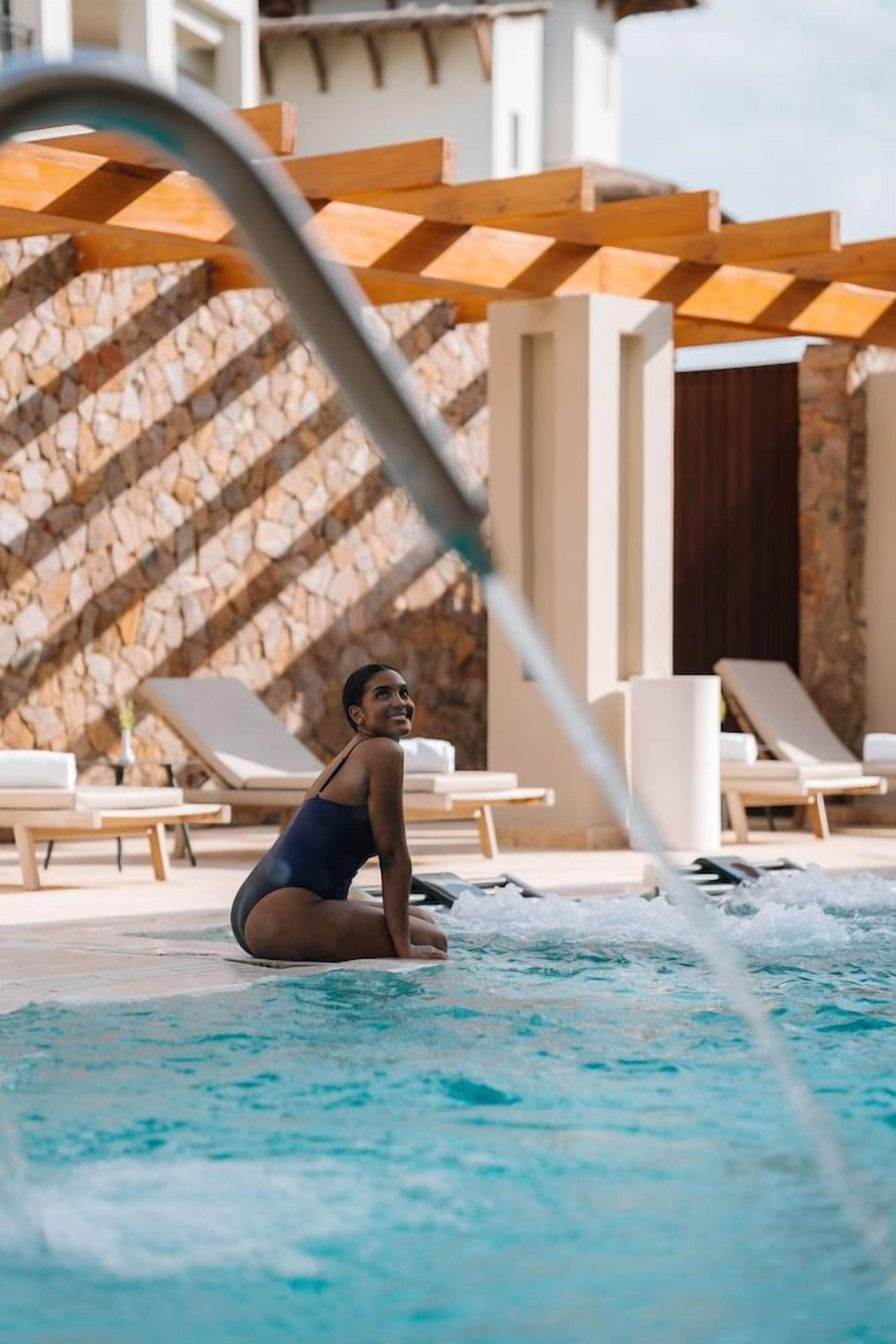 Un área de piscina con sillas de descanso y una pared de piedra.