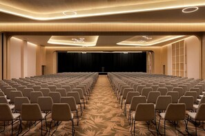 A conference room with rows of chairs, a stage, and a carpeted floor. - Secrets Playa Esmeralda Resorts & SPA (Miches)