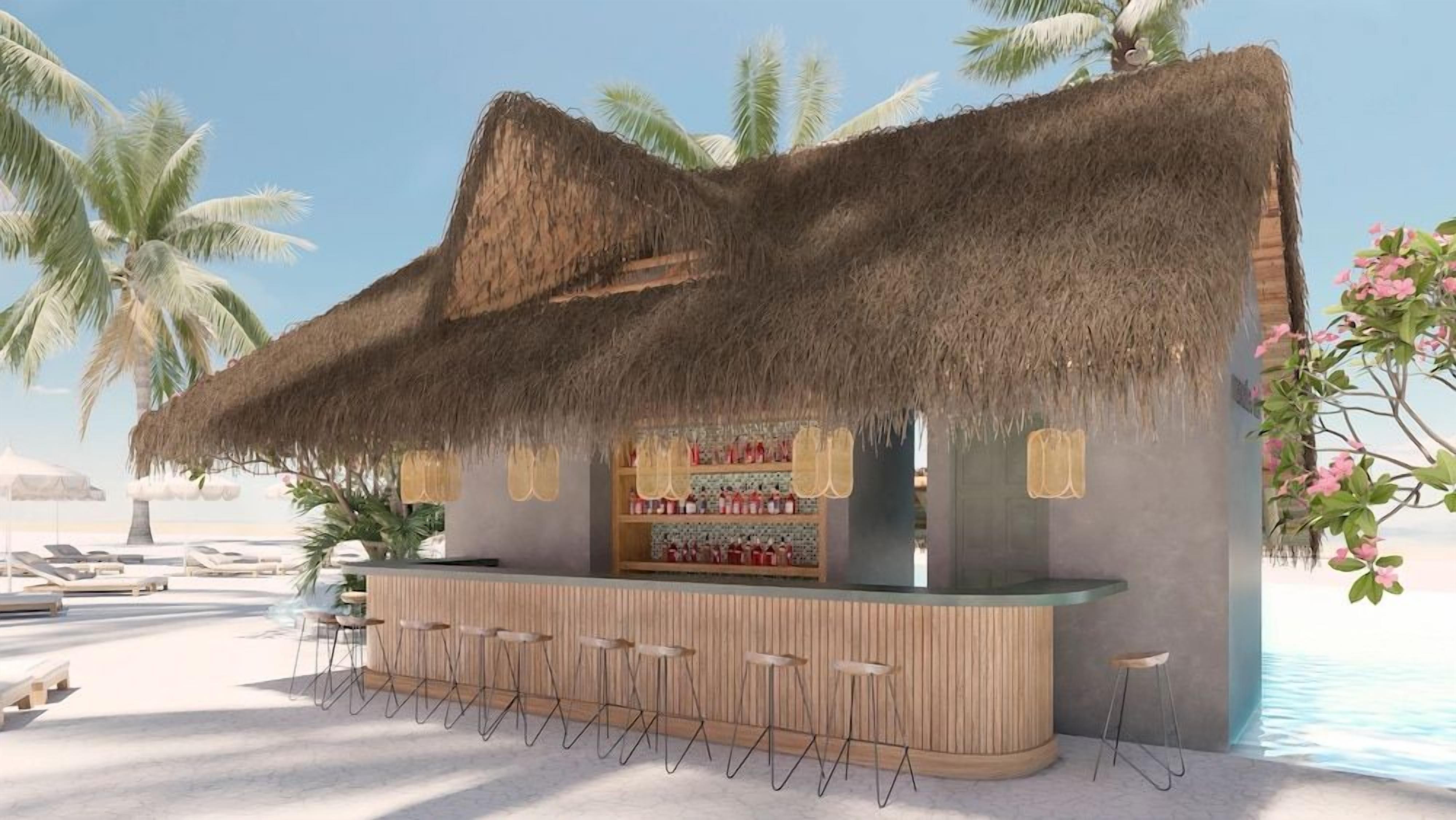 A beachside bar with a thatched roof, bar stools, and a shelf with bottles.
