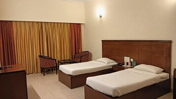 A hotel room with two beds, a desk, a chair, and a curtain.