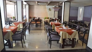 Un restaurante con numerosas mesas y sillas, dispuesto en un espacio amplio.
