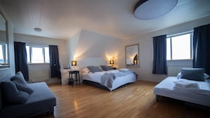 A modern bedroom with a large bed, a sofa, a desk, and a mirror. - Framnes (Grundarfjörður)