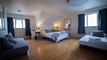 A modern bedroom with a large bed, a sofa, a desk, and a mirror.
