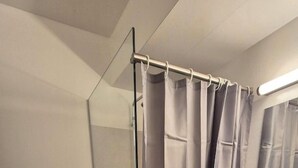 A bathroom with a toilet, a sink, a shower curtain, and a mirror. - Framnes (Grundarfjörður)