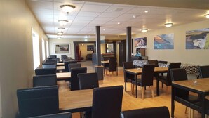 A restaurant with multiple tables and chairs, a counter area, and artwork on the walls. - Framnes (Grundarfjörður)