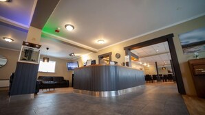 A reception area with a curved counter, seating area, and a television. - Framnes (Grundarfjörður)