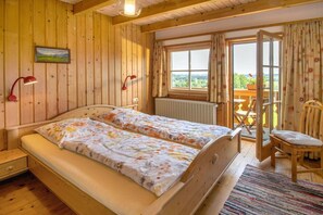 A wooden room with a bed, a chair, a table, and a window with curtains. - Sympathy at the Striegl guesthouse (Wertach)