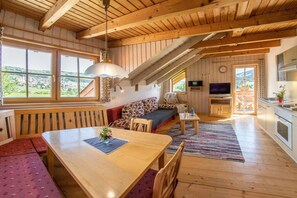 A wooden interior with a dining table, sofa, and kitchen area. - Sympathy at the Striegl guesthouse (Wertach)