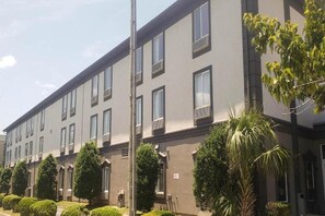 A multi-story building with a symmetrical facade, evenly spaced windows, and a series of trees in front. - Motel6 Mobile, AL Airport Blvd (Mobile)
