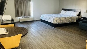 Una habitació d'hotel amb llit, escriptori, cadira i finestra amb cortines.