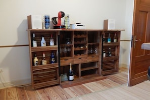 A wooden wine rack with multiple shelves and drawers, some containing bottles and glasses. - Holiday home with 4 bedrooms (Hundsdorf)