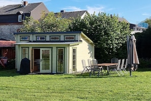 Een laag, klein gebouw met een overdekte patio, een tafel en stoelen.