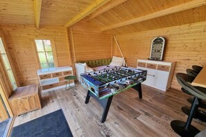 Um quarto aconchegante com mesa de pebolim, sofá, armário pequeno e janela.