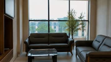 A modern living room with a large window, two sofas, a coffee table, and a television.