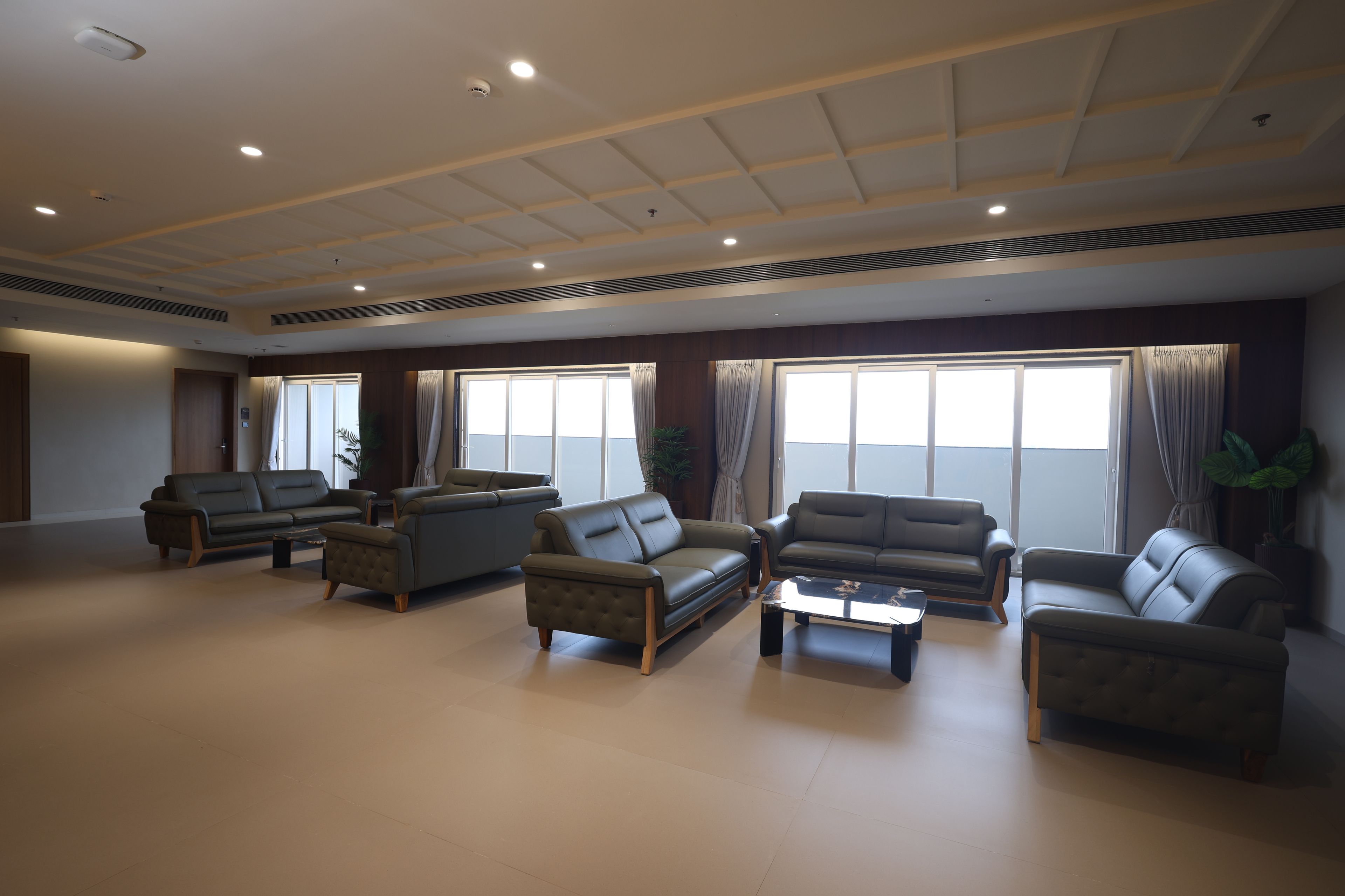 A spacious living room with multiple sofas and armchairs arranged around a central coffee table.