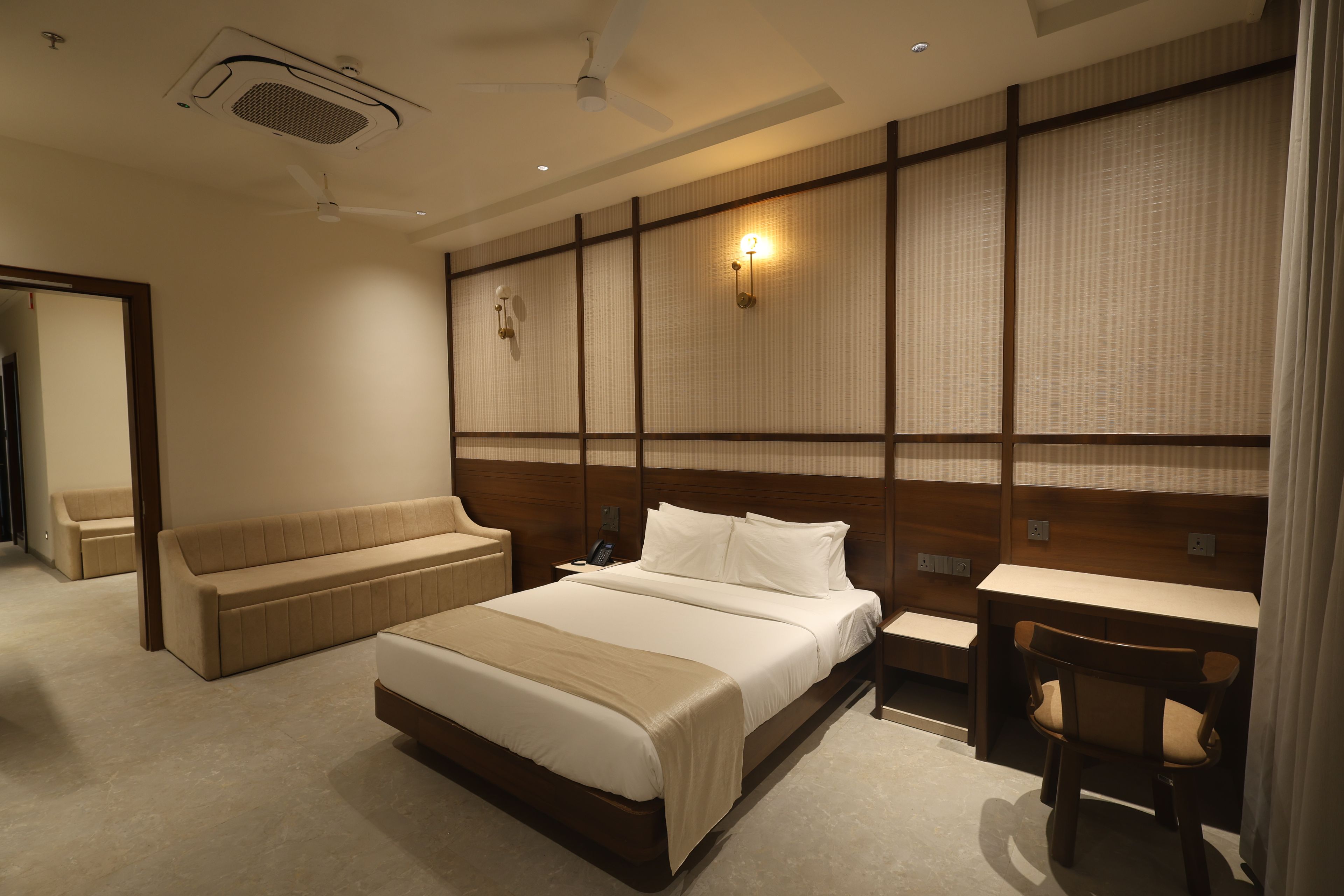 A hotel room with a bed, a sofa, a desk, and a chair.