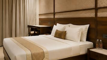 A hotel room with a large bed, a desk, and a nightstand.