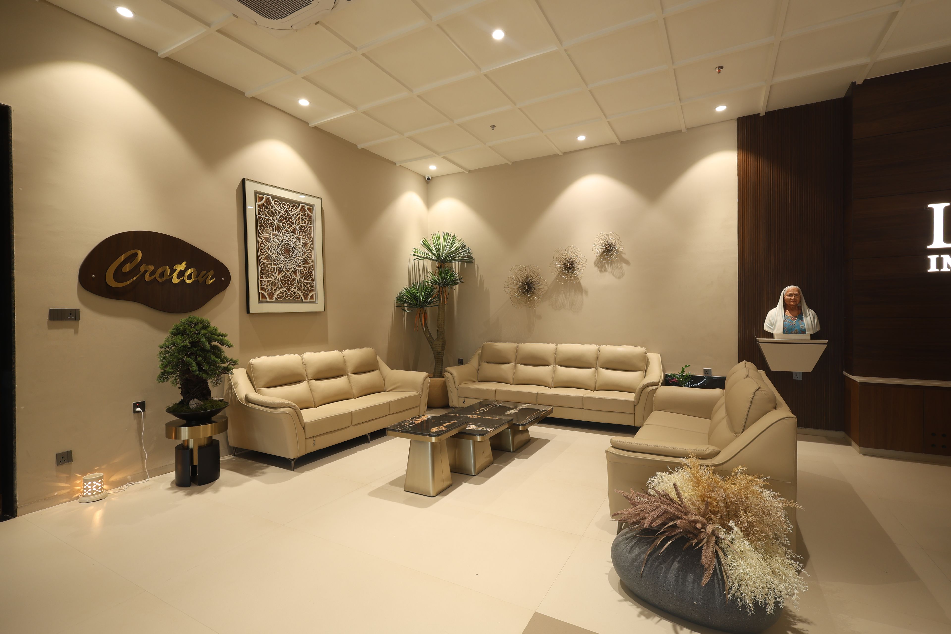 A modern interior with a beige sofa set, a coffee table, and decorative plants.