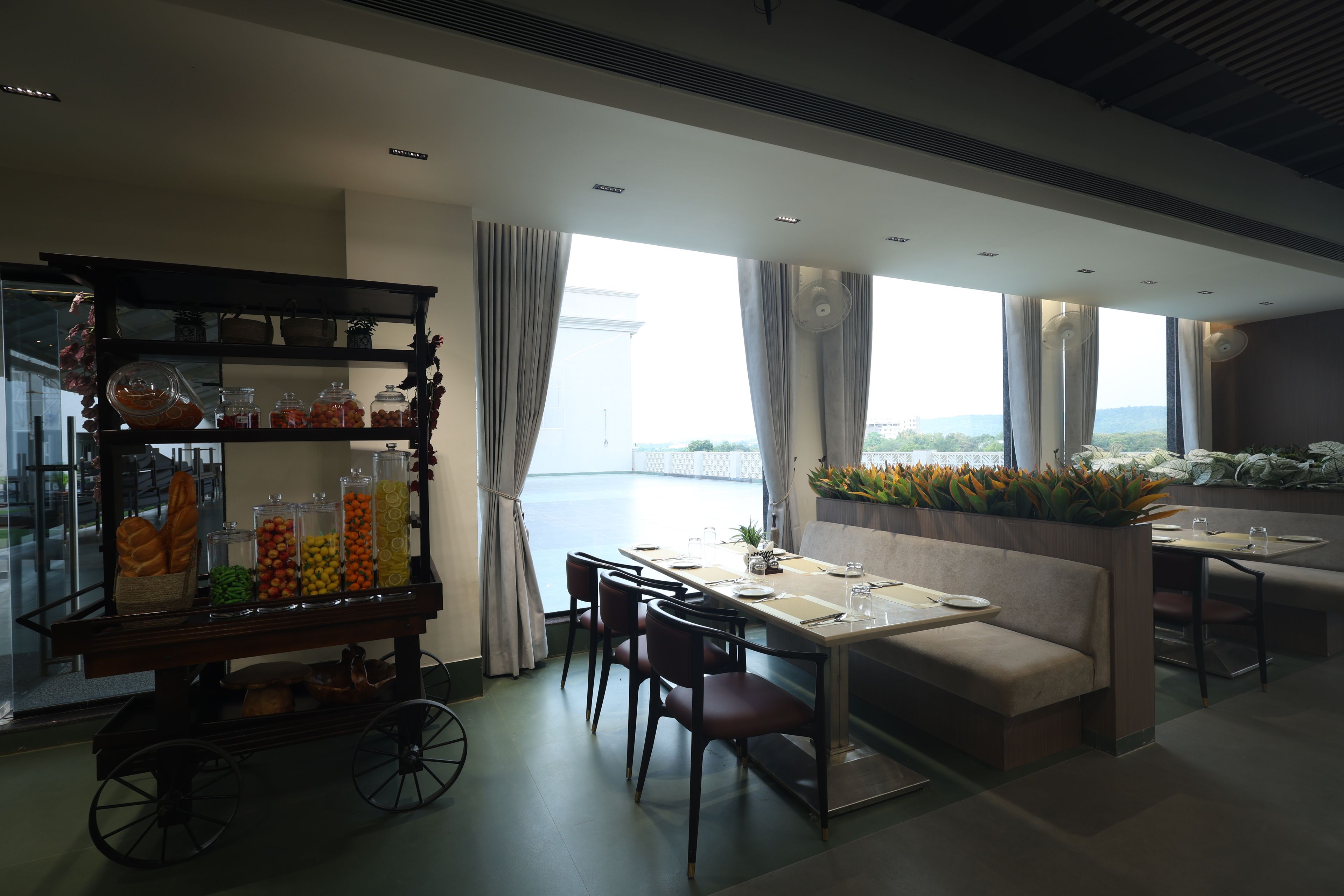A modern dining area with a view of the sea, a buffet with various food items, and a seating arrangement with tables and chairs.