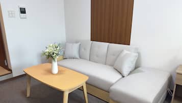 A modern living room with a sofa, a wooden coffee table, and a vase of flowers.