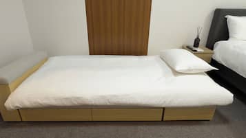Habitación estándar de hotel con una cama individual, una mesita de noche con control remoto y un cabecero de madera.