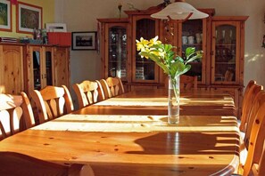 Ein Holztisch mit Stühlen, eine Vase mit Blumen und Holzschränke im Hintergrund.