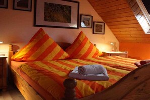 Ein Bett mit gestreifter Bettwäsche, ein aufgerolltes Handtuch und ein Holzkopfbrett.