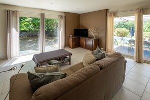 Ein Wohnzimmer mit einer Couch, einem Couchtisch und einem Fernseher auf einer Holzkommode.