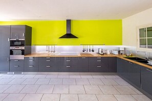 Eine moderne Küche mit grauen Schränken, einer schwarzen Dunstabzugshaube und einer leuchtend grünen Wand.