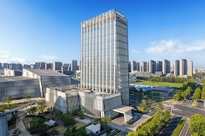 A modern high-rise building with a glass facade, surrounded by other high-rise buildings and greenery. - Intercontinental Wuxi Taihu New City (Wuxi)