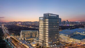 A modern high-rise building with a glass facade, surrounded by a well-lit urban area with other high-rise buildings. - Intercontinental Wuxi Taihu New City (Wuxi)