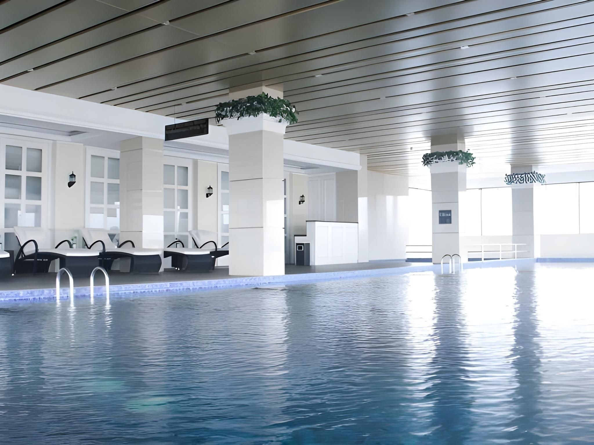 An indoor swimming pool with clear water, lounge chairs, and a modern architectural design.