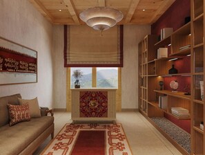 A room with a sofa, a patterned rug, a bookshelf, and a window with a view. - Taj Gangtey Resort & Spa, Bhutan (Wangdue Phodrang)