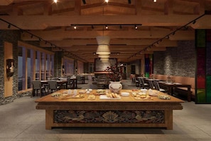 Un restaurant doté d’une grande table centrale où sont disposés différents plats, entourée de chaises.