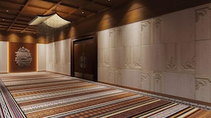 Un couloir doté d’un tapis à motifs, d’un grand mur décoratif et d’une porte au décor ouvragé.