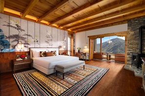 Un dormitorio espacioso con una cama grande, una chimenea de piedra y vistas a las montañas.
