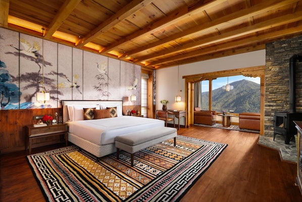 Une chambre spacieuse avec un grand lit, une cheminée en pierre et une vue sur les montagnes.