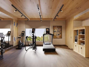 A gym with exercise equipment, a treadmill, and a wooden ceiling. - Taj Gangtey Resort & Spa, Bhutan (Wangdue Phodrang)
