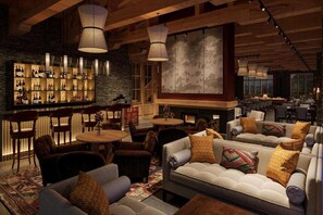 Un rincón acogedor de bar con vigas de madera, chimenea y asientos cómodos.