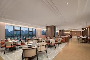 A modern restaurant with high ceilings, large windows, and a variety of seating arrangements. - Hilton Garden Inn Lanzhou Anning (Lanzhou)