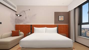 A modern hotel room with a large bed, a sofa, a nightstand, a wall-mounted lamp, and a city view.