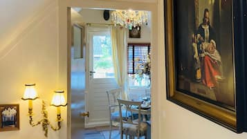 A hallway with a dining area, a chandelier, and a framed painting.