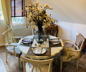 A dining table set for four with a vase of flowers, surrounded by chairs with a musical theme. - 1001 nacht (Bruinisse)