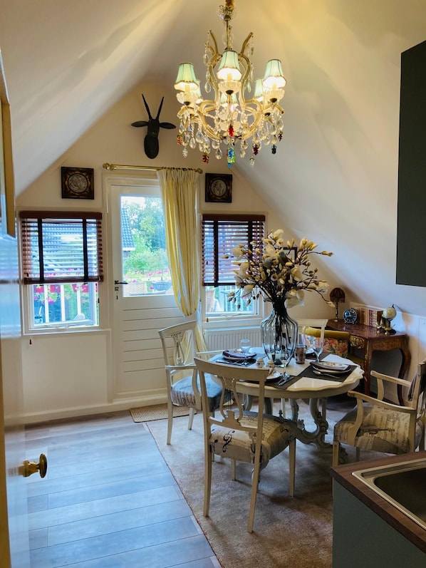 A dining area with a chandelier, a door with a deer head decoration, and a window with blinds.
