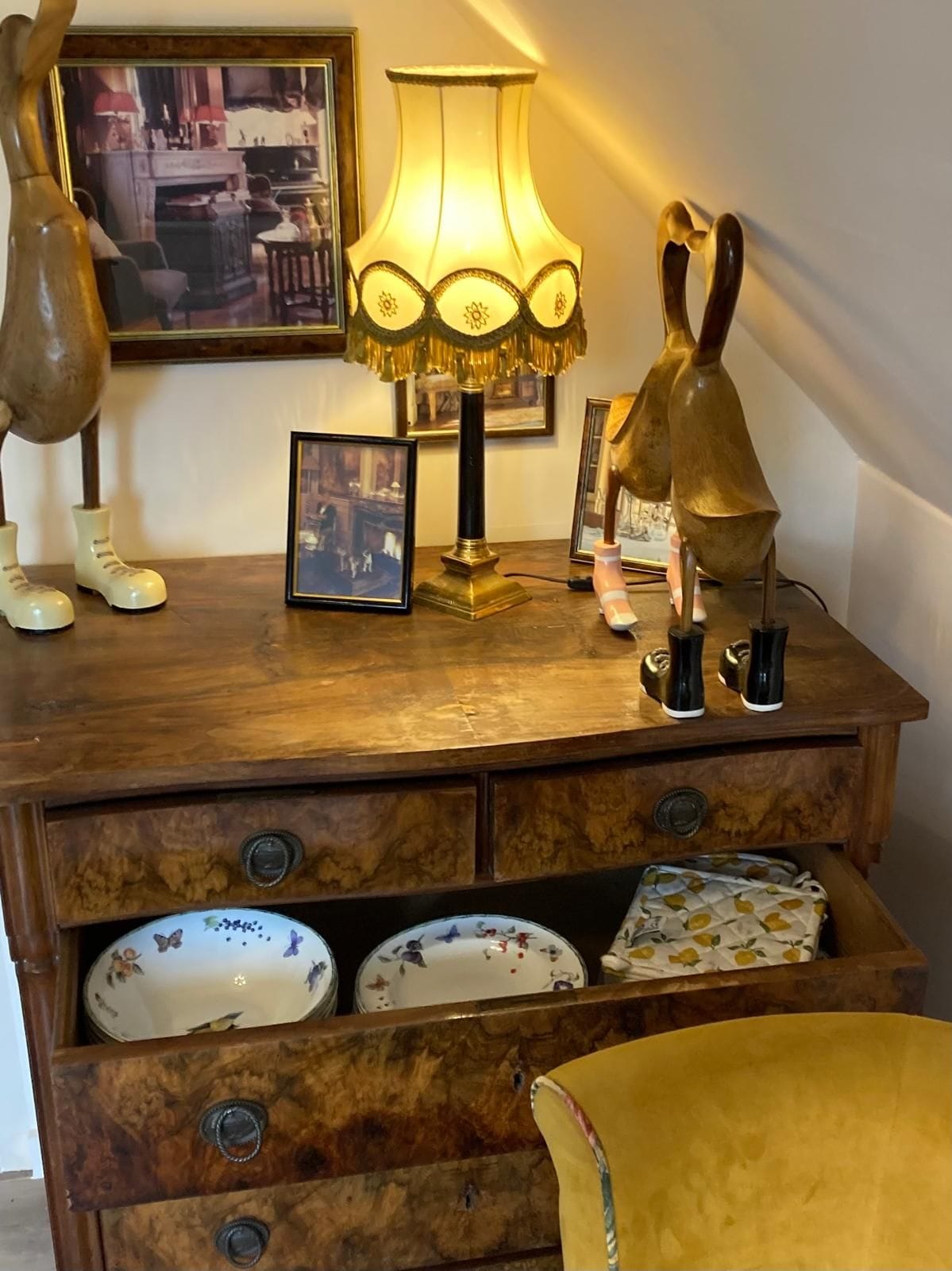 A wooden dresser with drawers, a lamp, and decorative items.