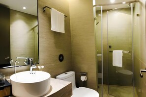 Un baño moderno con un lavamanos grande, inodoro y cabina de ducha de vidrio.