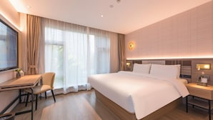 Habitación de hotel con una cama grande, un escritorio con silla, un televisor y una mesita de noche con lámpara.